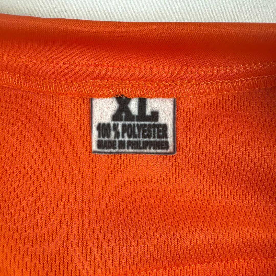 Close-up of orange fabric with a size label indicating XL and 100% polyester, made in the Philippines.