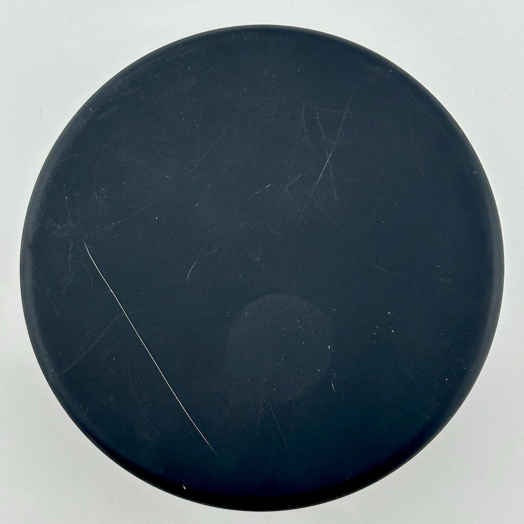 Underside of black circular tin with a few scratches.
