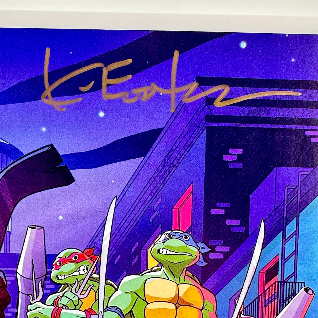 Close up of top of comic book cover with cartoon turtles with weapons in a cityscape at night, signed by Kevin Eastman.