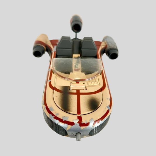 A vintage toy model of a futuristic spacecraft, featuring a weathered tan and red paint scheme.