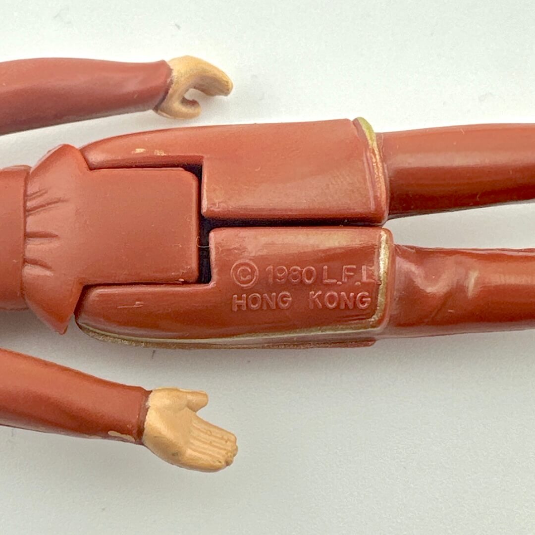 Close-up of a red action figure arm with a visible copyright and 'Hong Kong' stamp on a white background.