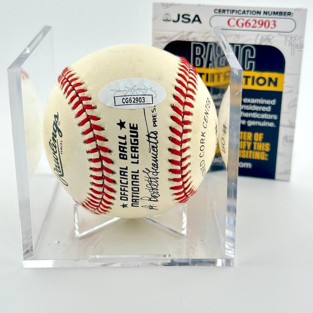 Signed baseball in clear display cube against white background, with JSA certificate and sticker