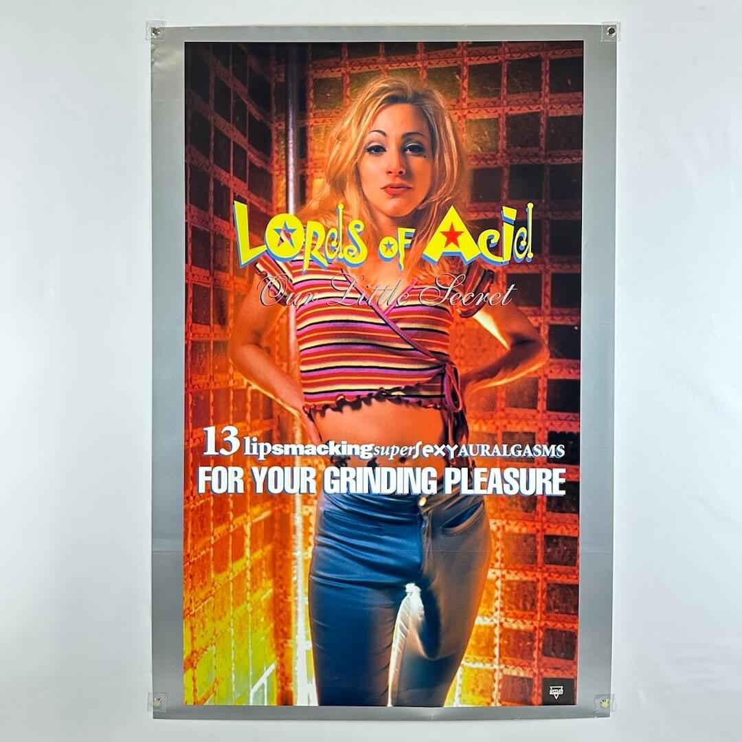 Poster for 'Lords of Acid' with a woman in a striped shirt and jeans on a brick wall background.
