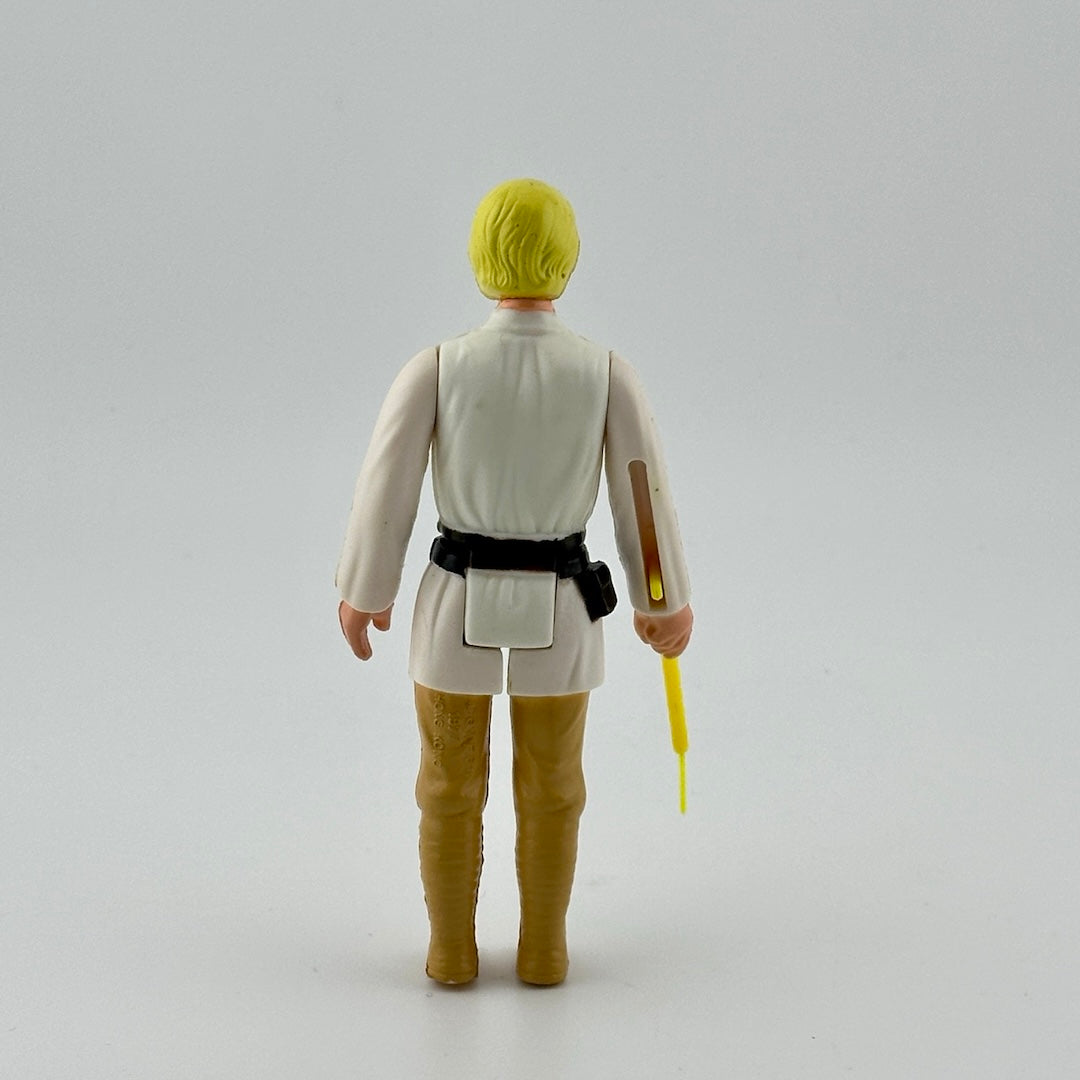 White male action figure with yellow hair in white shirt, black belt & tan pants, yellow lightsaber emerging from right hand.