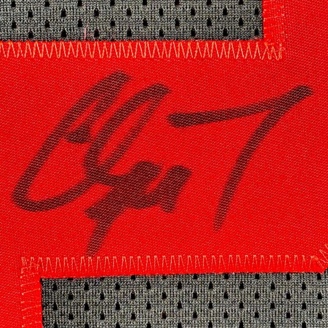 Close-up of a red fabric patch with black marker signature on a black jersey background