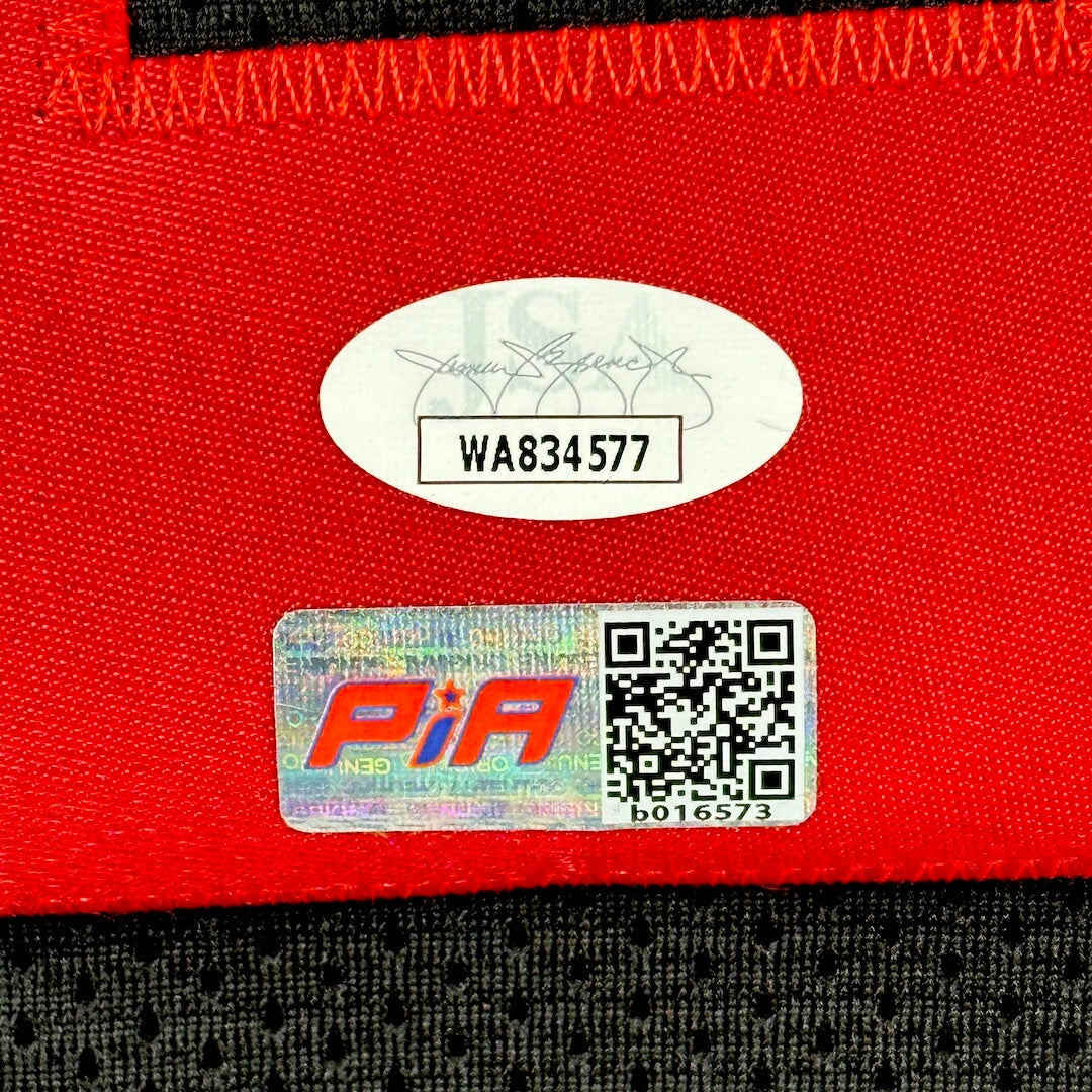 Close-up of a red fabric surface with authentication sticker and QR code on black jersey.