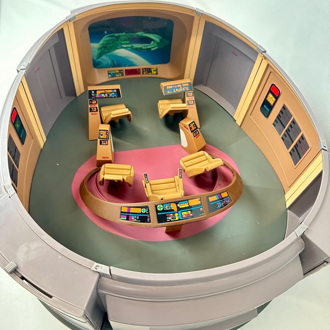 Model of a futuristic control room with a view of space on a screen.