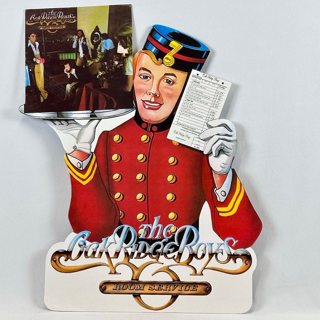 Reverse image Bellhop wearing red uniform and black hat. Holding record album on plater and check in other hand.