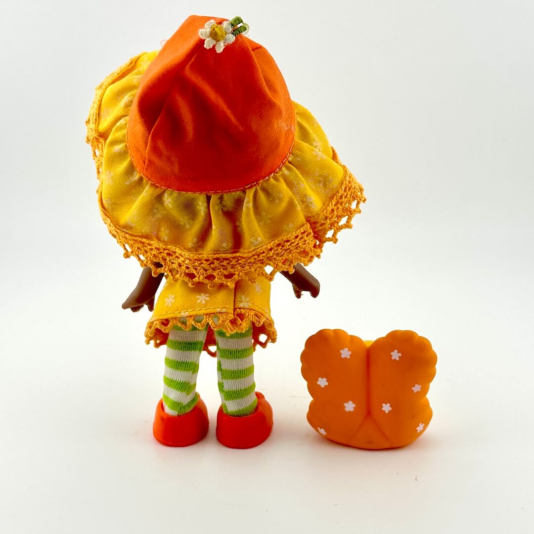 Small doll with an orange hat and dress on a white background