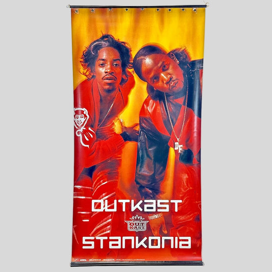 Promotional banner for Outkast featuring two individuals with a red and yellow background.