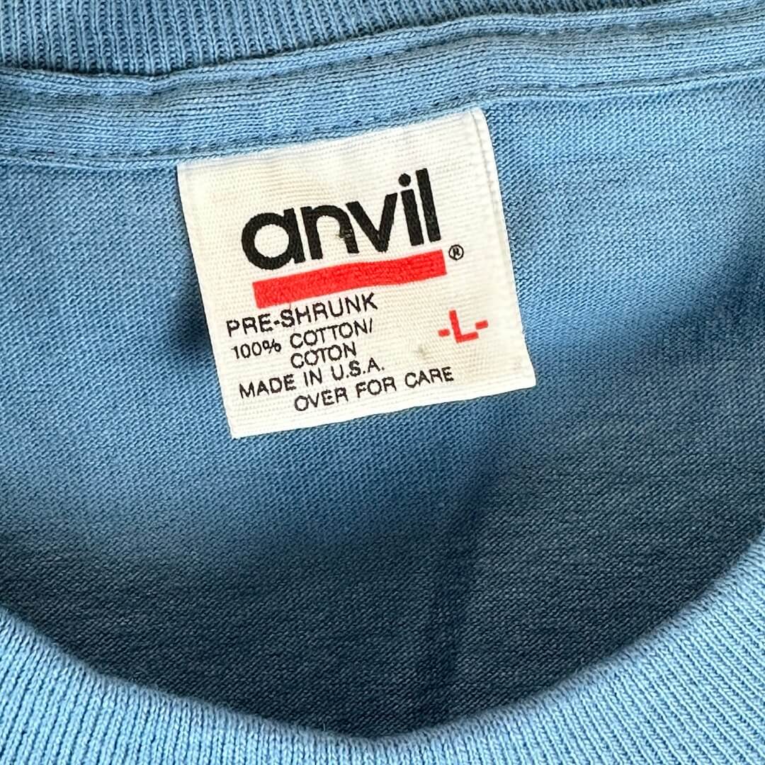 Close-up of the tag on a 1995 Pearl Jam tour t-shirt from the Missoula, MT concert. The tag displays the Anvil brand, size large (L), 100% pre-shrunk cotton, made in the U.S.A.
