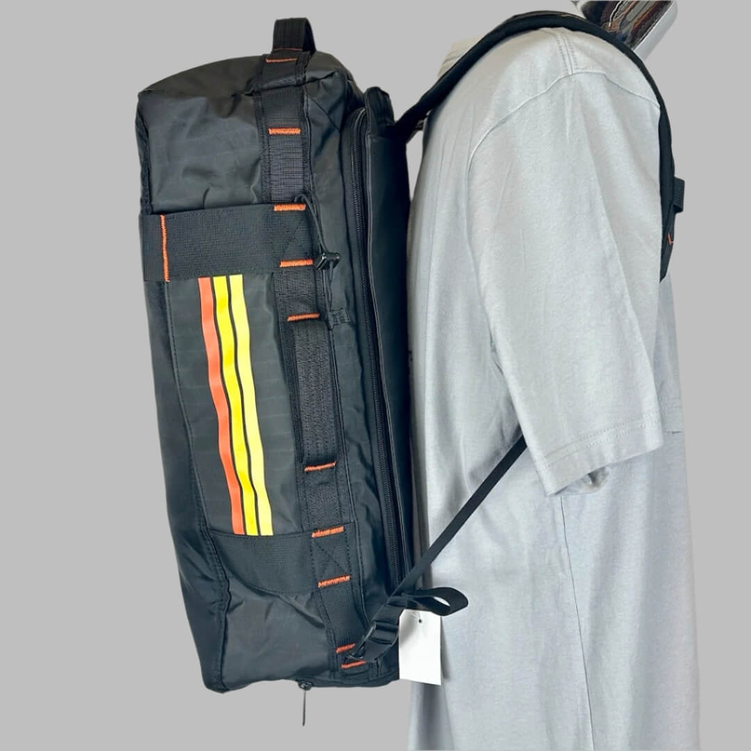 Other side of black backpack showing the orange & yellow stripe details under handle, & orange stitch details.