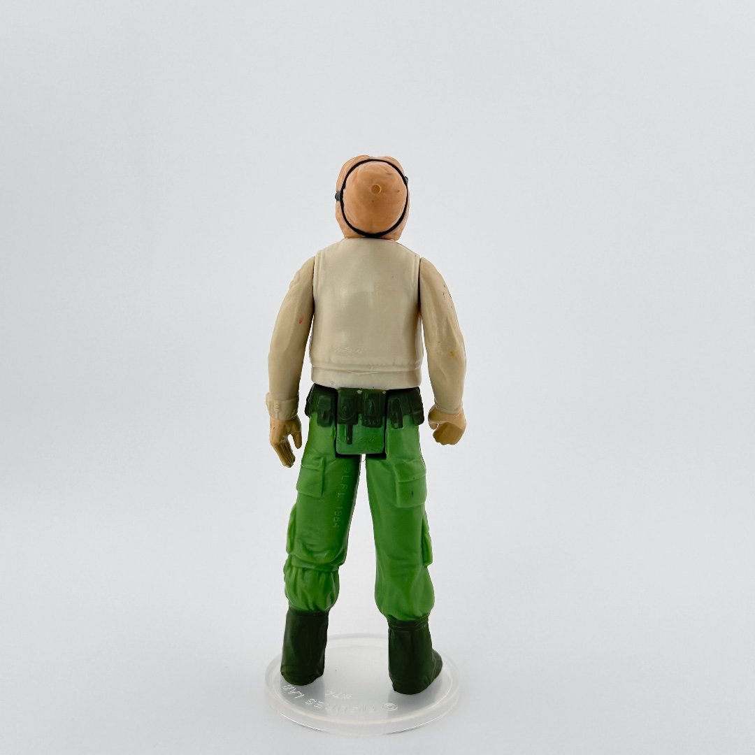 Reverse image of 3 inch figure wearing green pants, black boots, beige long sleeved shirt, peach flesh tone, black headband.