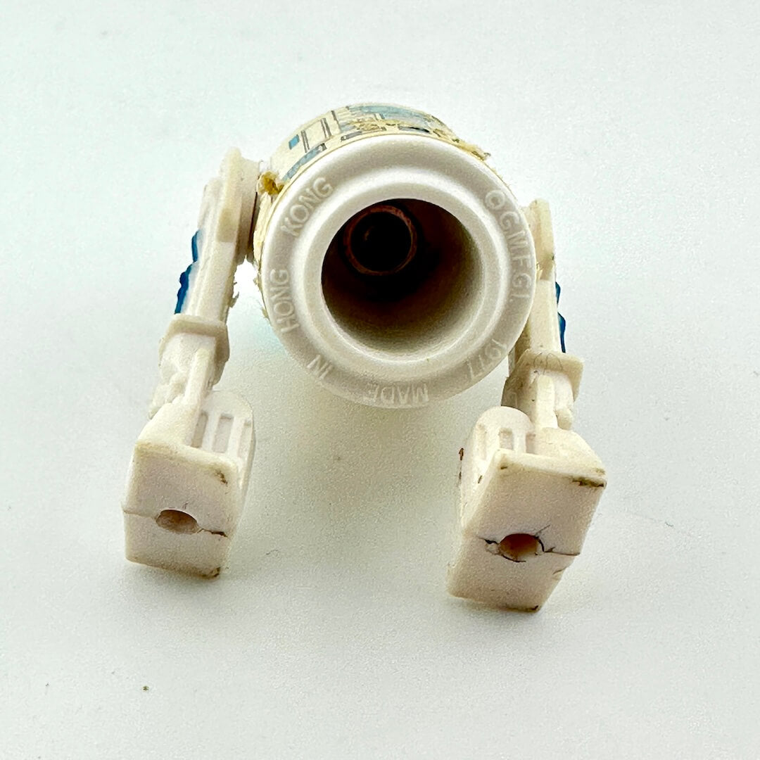 A vintage white plastic toy R2-D2 showing signs of wear and age, with some scuffs and dirt visible