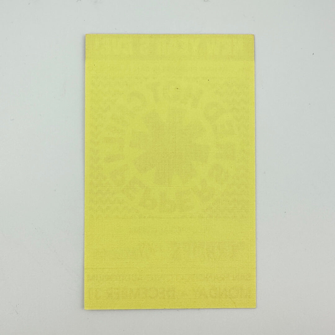 Backside of yellow event ticket against white background showing no damage to ticket.