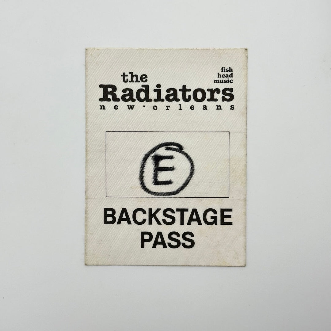 White rectangular fabric backstage pass with black print with event information in basic text, circled "e" in center.