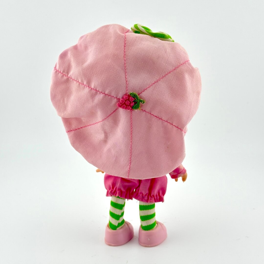 Toy figure with a pink flower hat and green striped socks on a white background