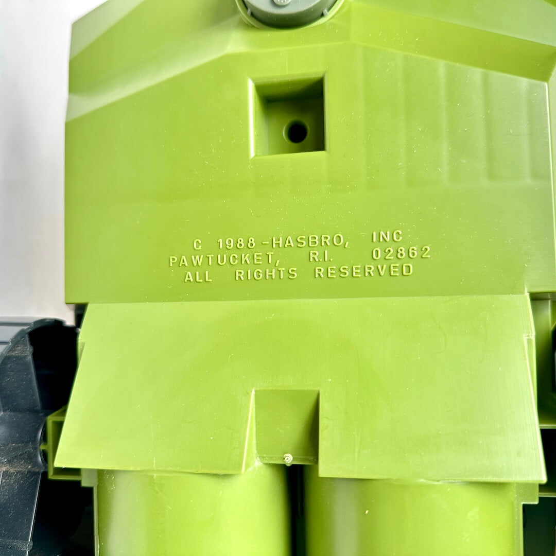 Green plastic toy with 'Hasbro' branding and text on a white background