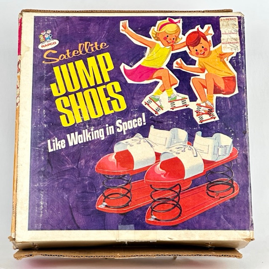 Cardboard box with illustrations of boy & girl jumping with spring bottom shoes, & closer image shoes. Yellow & white text.