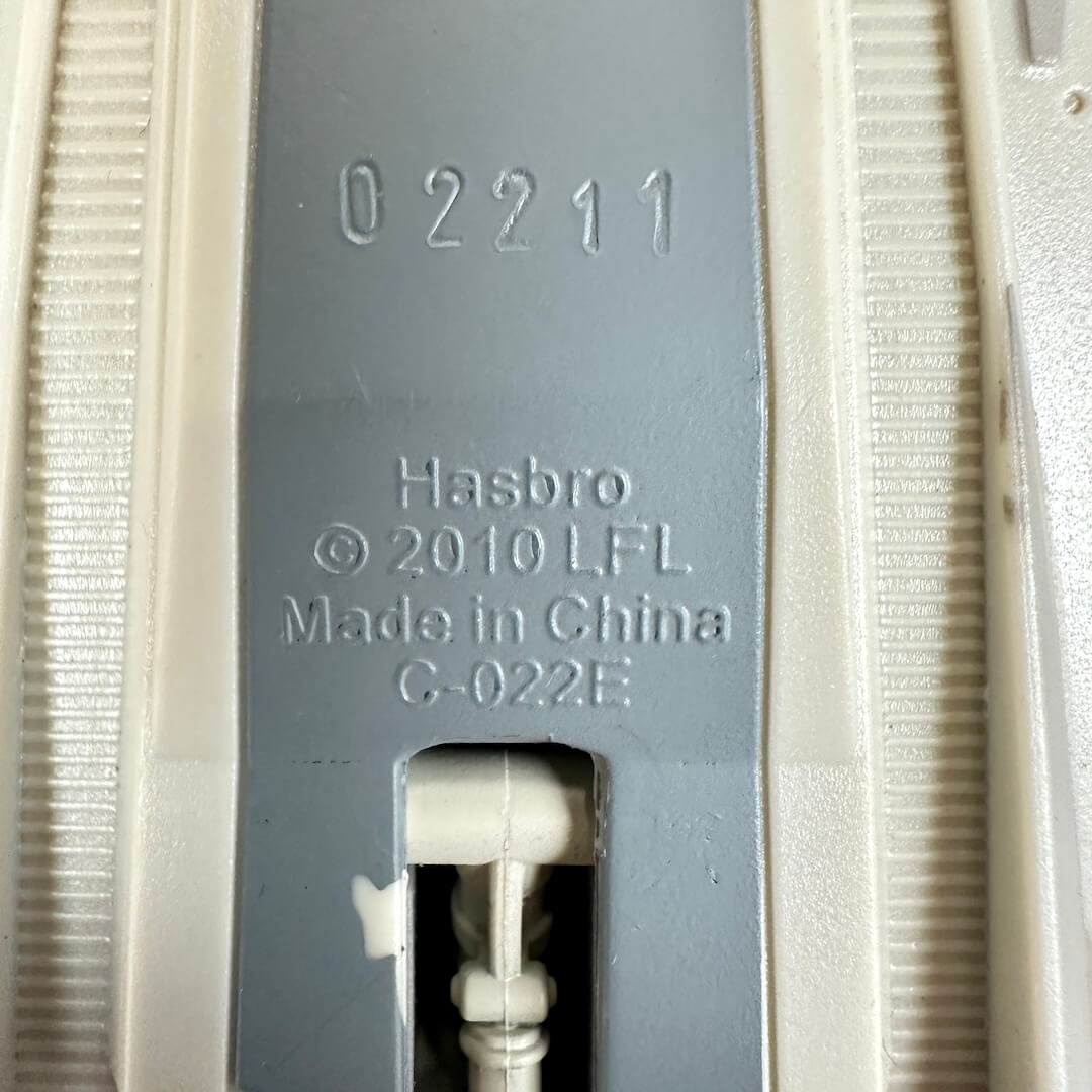 Close-up of gray plastic with embossed text reading '02211', 'Hasbro', '© 2010 LFL', 'Made in China', and 'G-022E'.