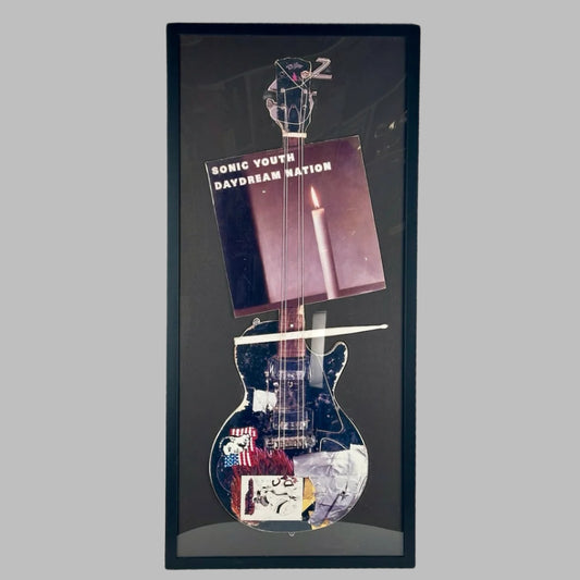 Guitar with drumstick & Daydream Nation album cover cardboard cutout set into black mat in black frame.