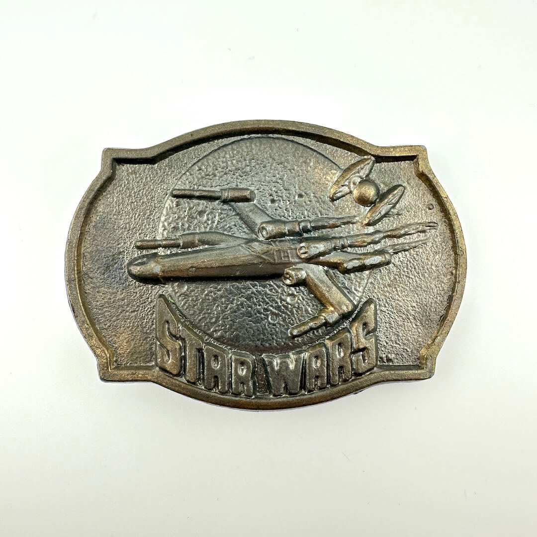 Metallic 'Star Wars' belt buckle with spaceship design on a white background