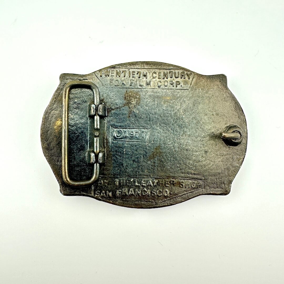 Vintage belt buckle with '20th Century Fox Film Corp.' branding on a white background