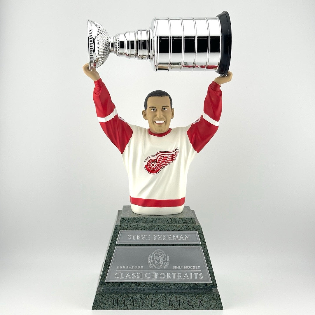 Faux marble pedestal with silver plaques, hockey player on top from stomach up, holding trophy above head.