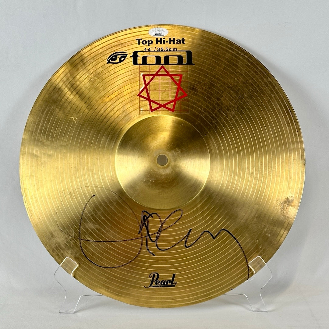 Gold percussion cymbal with black signature on bottom. Red square design sticker under black TOOL lettering.