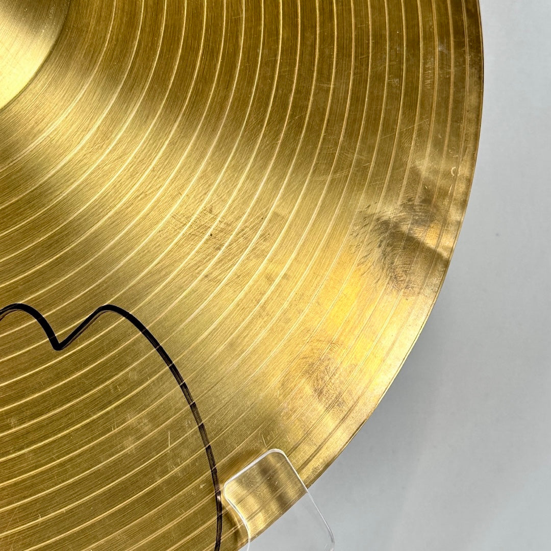 gold cymbal with signature and dent in the metal