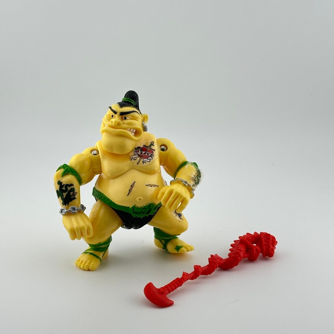 Sumo wrestler with tattoo stickers with chains around wrists, pictured with red accessory.
