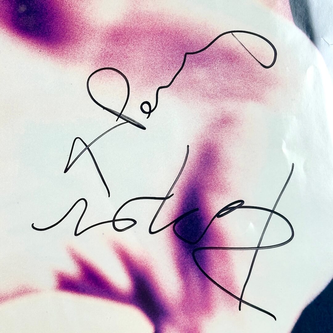 Two black signatures on palm of hand in poster.