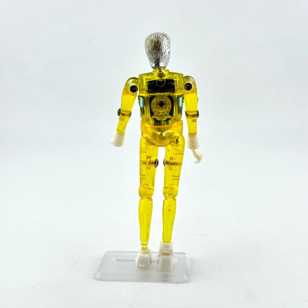A translucent yellow plastic humanoid action figure or droid standing on a clear plastic display base.