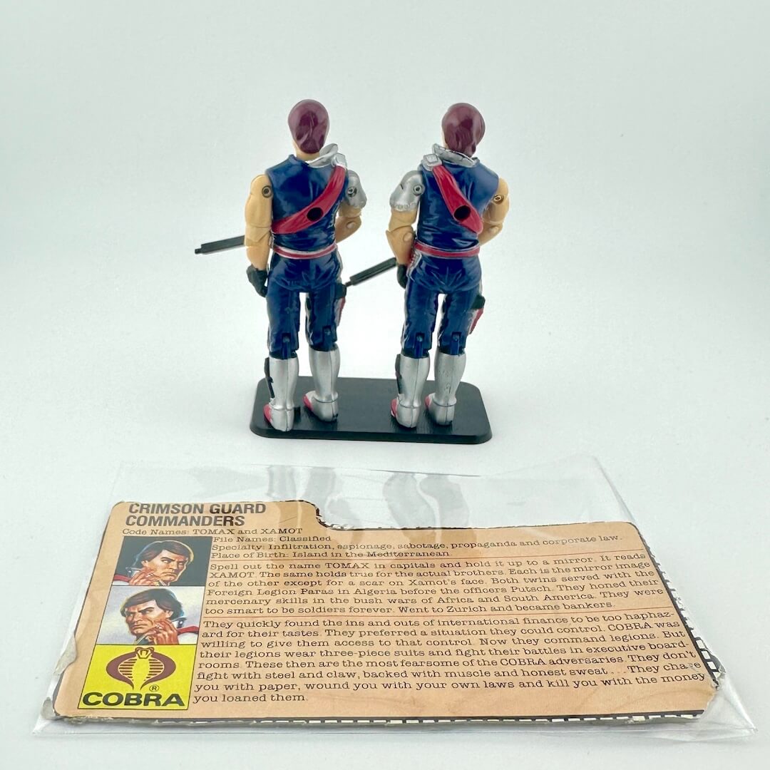Two toy figures of Crimson Guard Commanders with a card in front on a white background