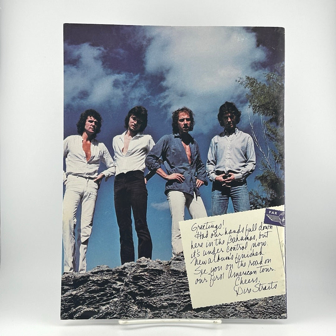 Four men standing on a cliff with blue sky in background, & handwritten postcard image at bottom right corner.