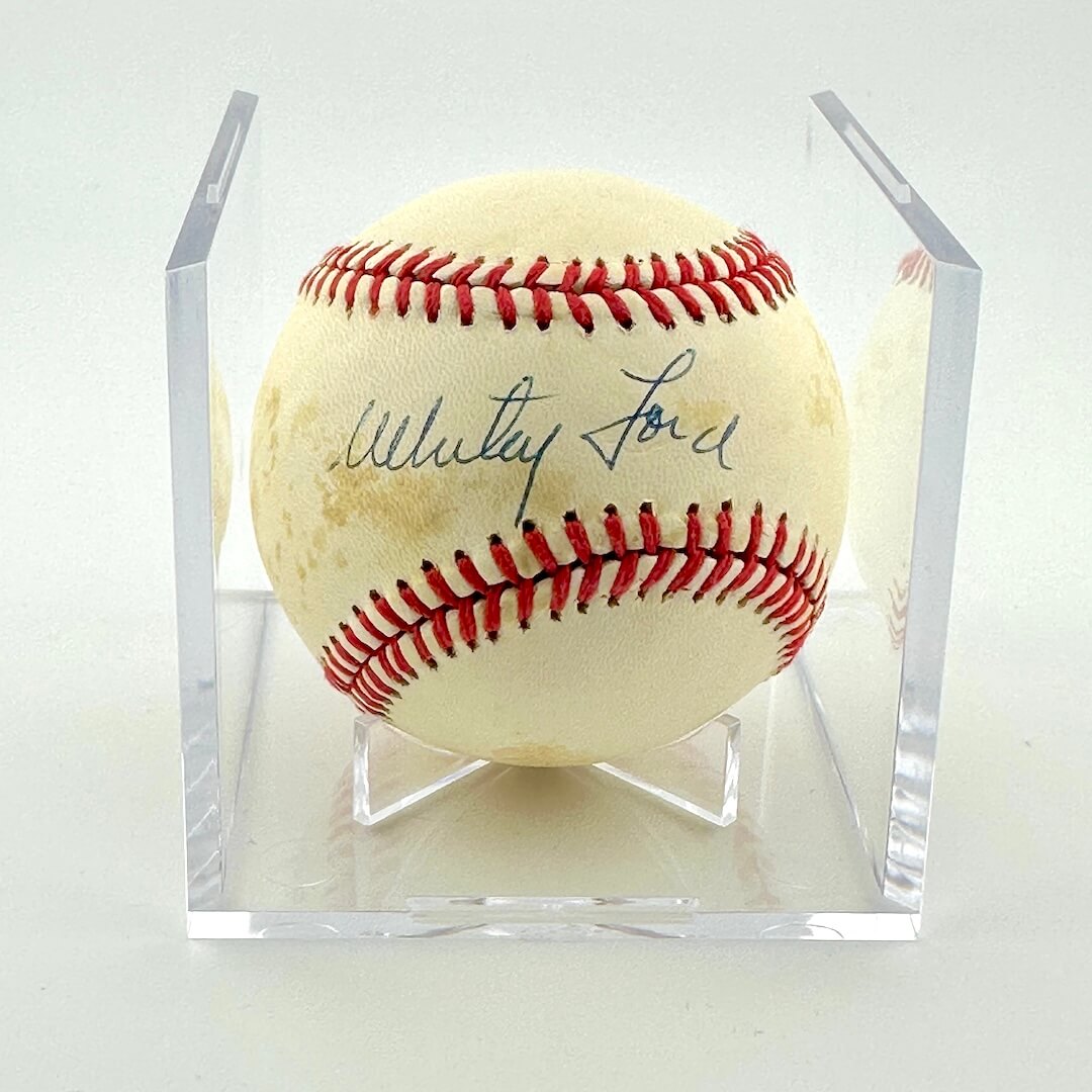 Signed baseball in clear display cube against white background.