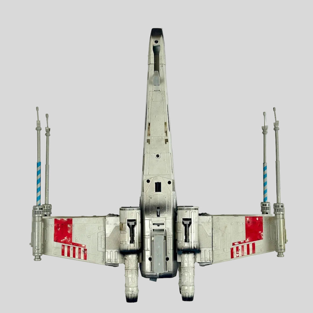 A detailed model of an X-wing Starfighter, photographed from the underside perspective.