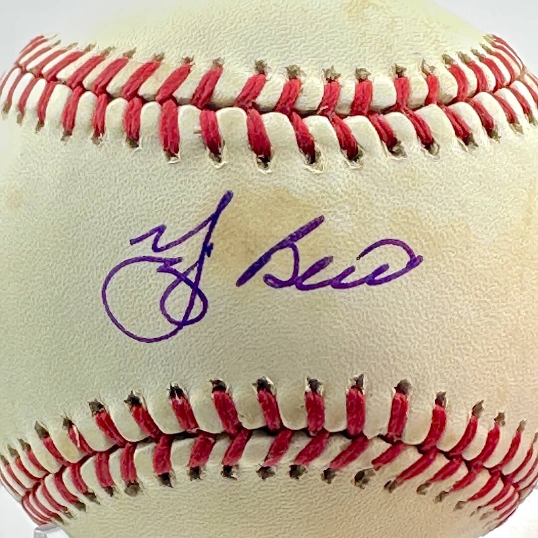 Signed baseball in clear display against white background, close up of signature across sweet spot.