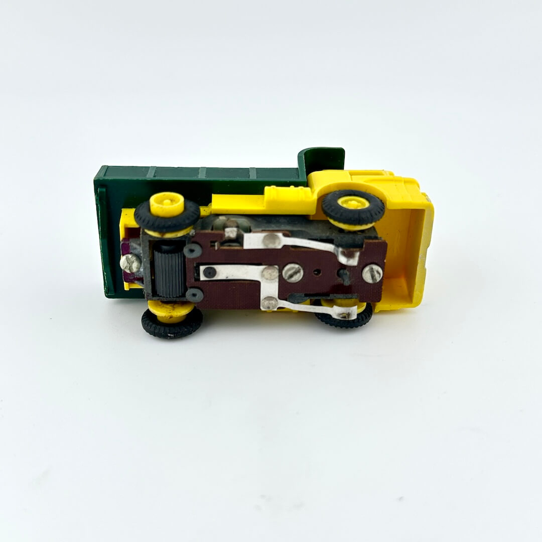 Toy construction vehicle with green body, yellow front, and black wheels on a white background