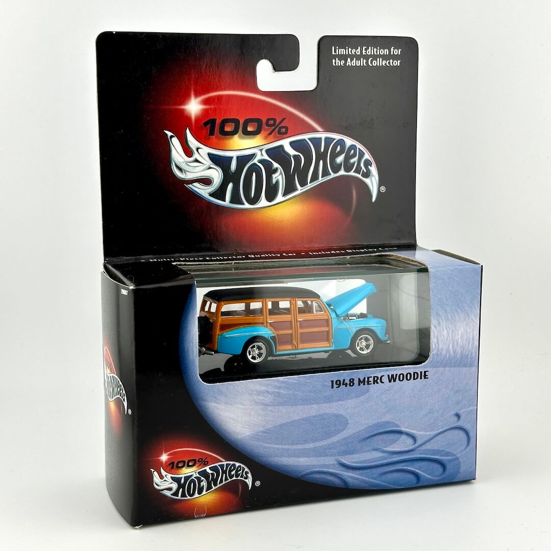 A Hot Wheels 1968 Merc Woodie diecast toy car in its original blister card packaging, featuring a blue car with wood panels. 
