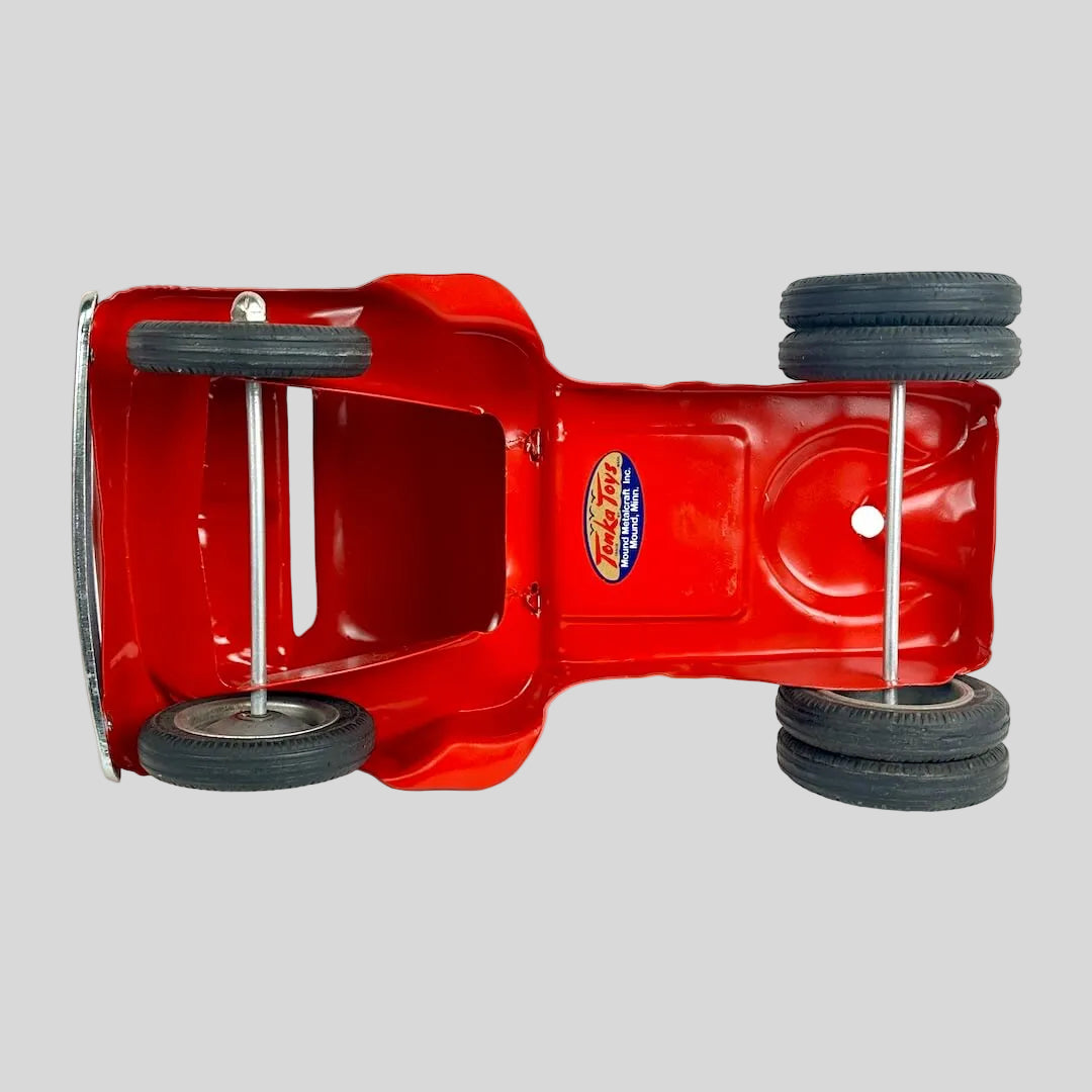 Underside of red toy truck against gray background. 