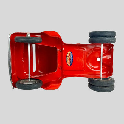 Underside of red toy truck against gray background. 