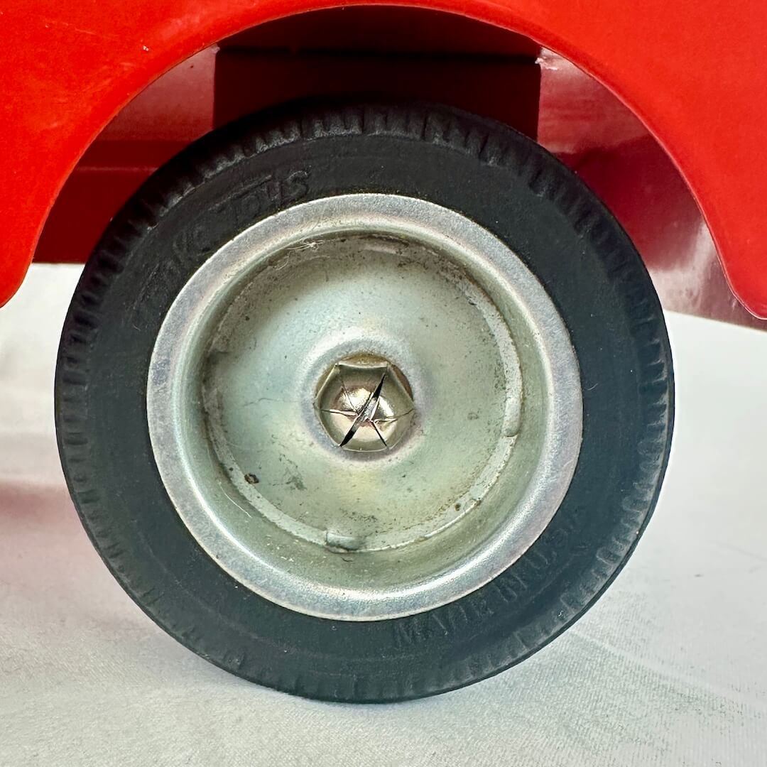 Close-up of a wheel with a red vehicle in the background