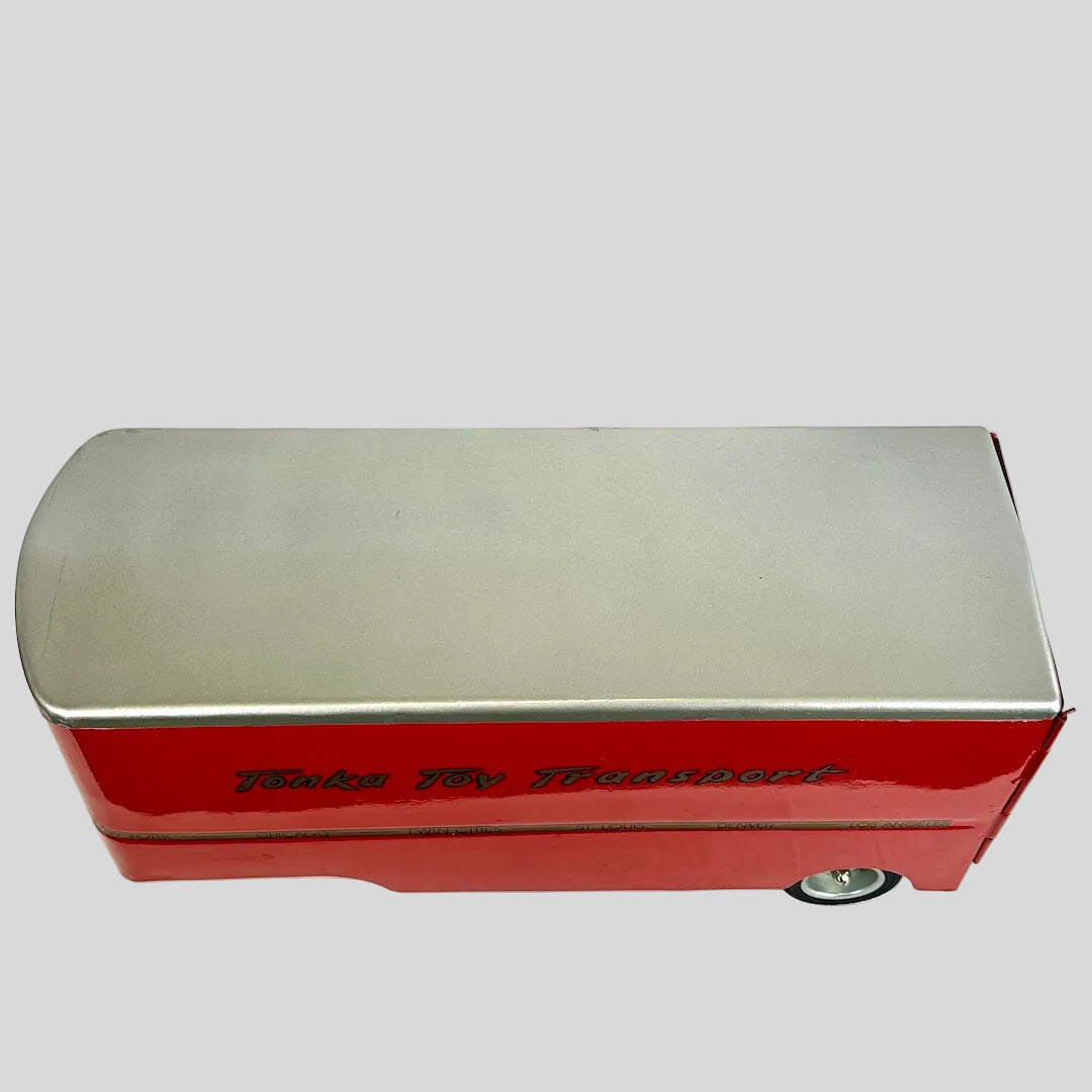 Topside of red toy transport trailer against gray background.