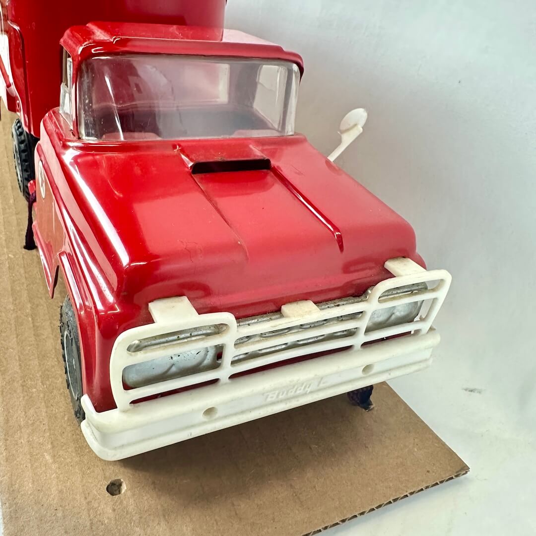 Red model truck on a cardboard surface with a white background