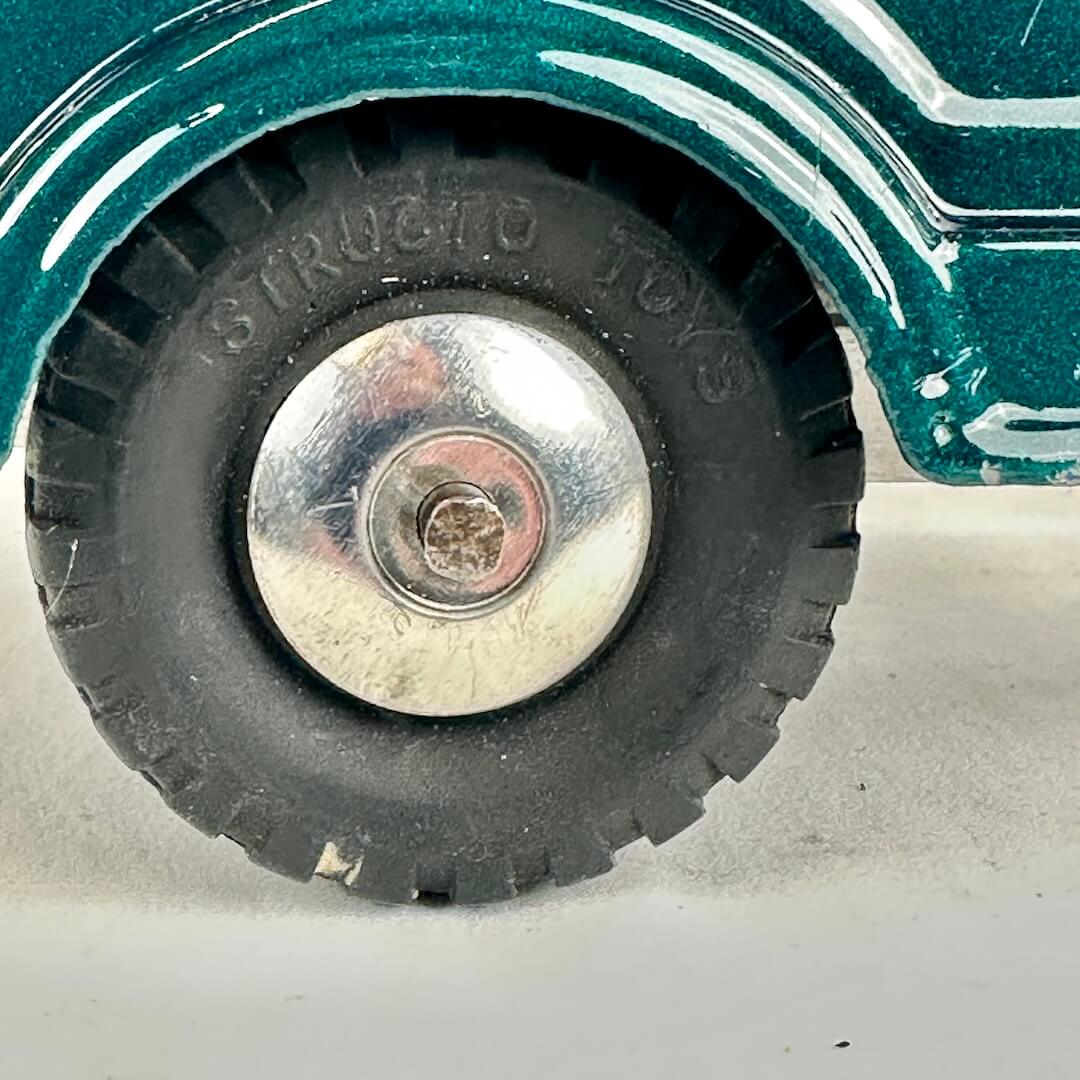 Close-up of a toy car wheel with 'Structo Toys' branding on a white background
