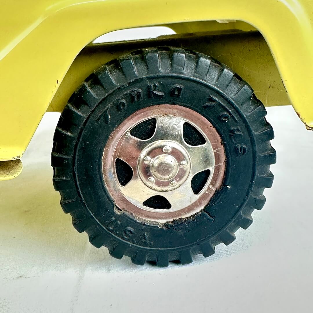 Close-up of a toy car wheel with a yellow body and black tire on a white background