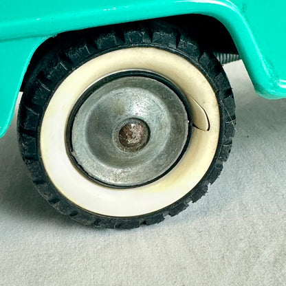 Close-up of a wheel with a green vehicle body on a light gray background