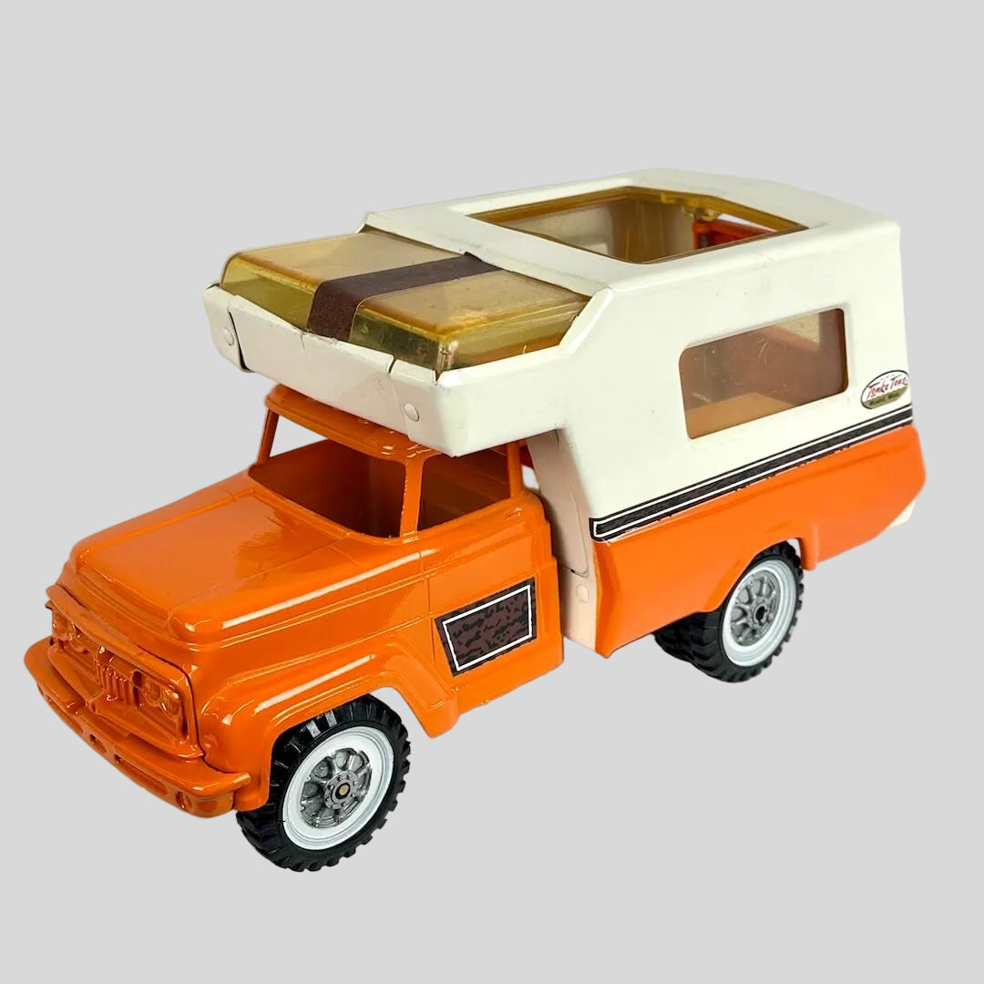 Toy camper truck with an orange body and white roof on a light gray background