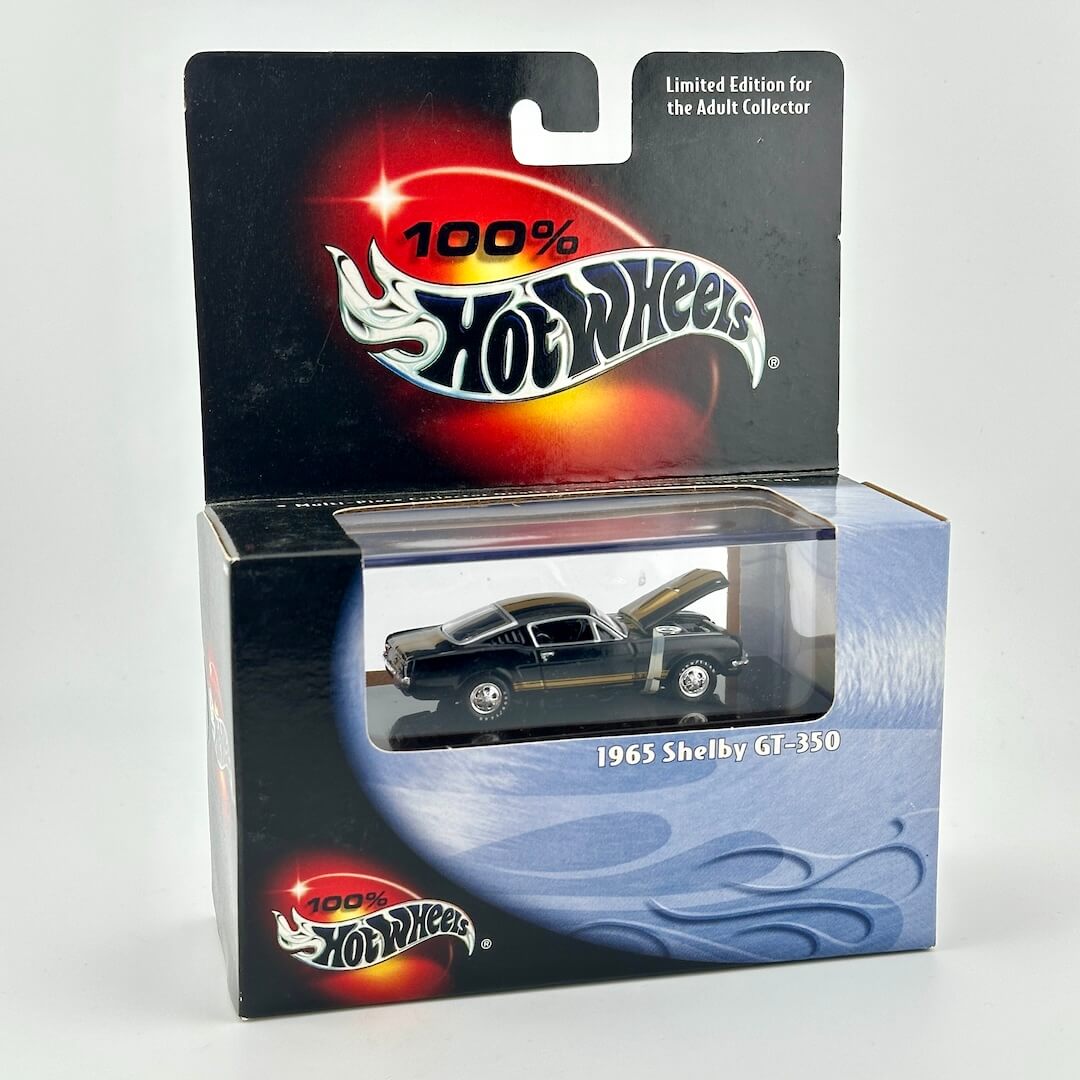 Hot Wheels 1965 Shelby GT-350 diecast car in its original packaging, featuring a black and gold car with its hood open.